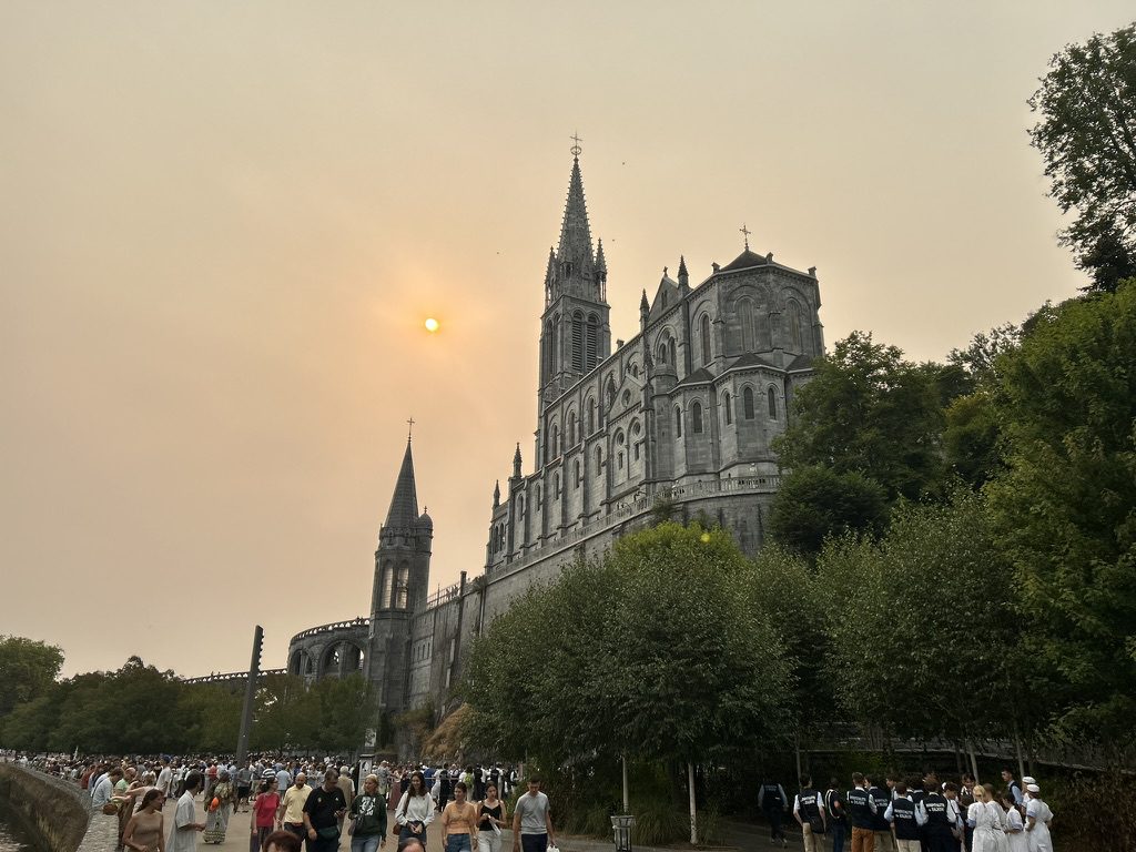 Peregrinos caminhando para o santuário de Lourdes ao entardecer